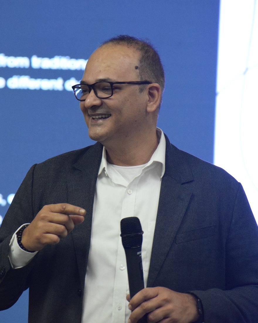 Dr. Vivek S. speaking on stage with a microphone